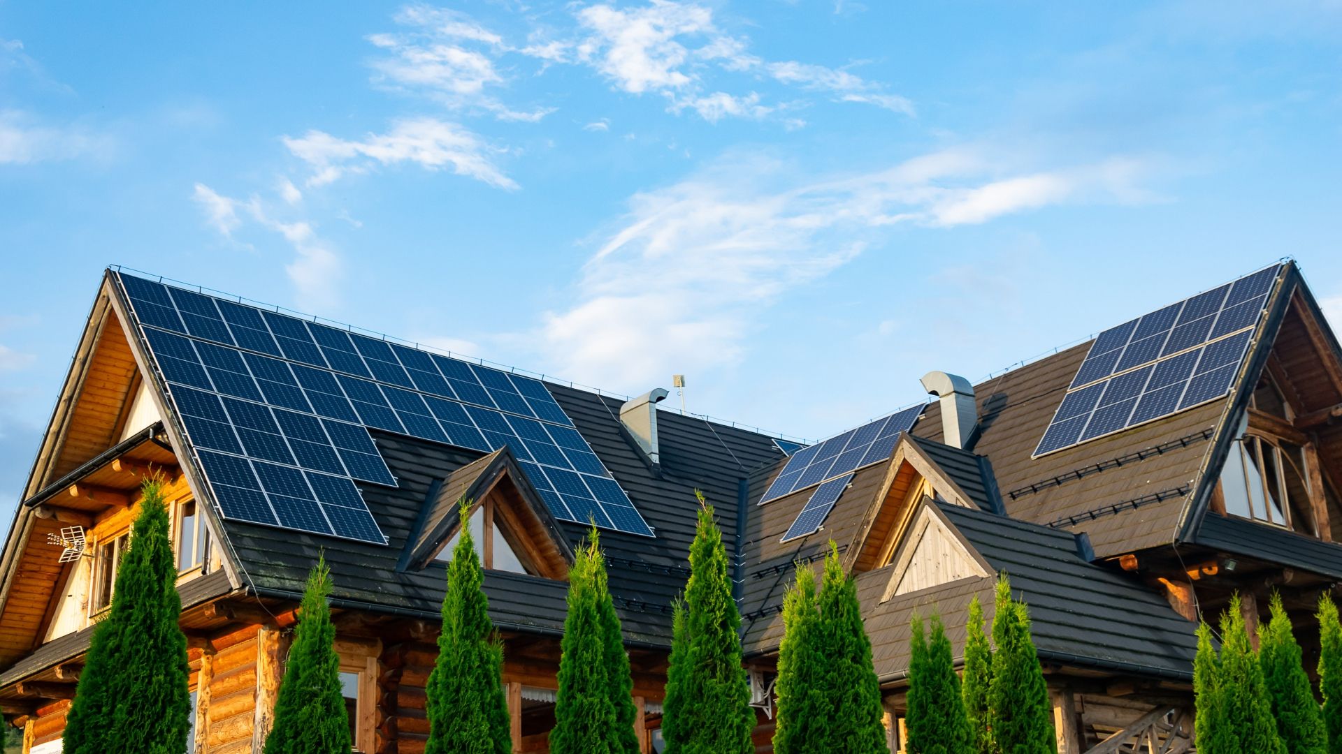 Holzhaus mit großen Solarpanelen auf dem Dach an einem sonnigen Tag